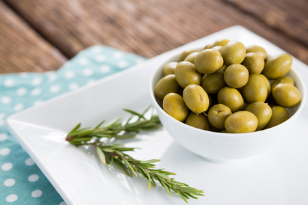 Close-up of marinated olives with rosemary on trayの写真素材