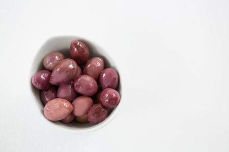 Close-up marinated olives in bowl against white backgroundの写真素材
