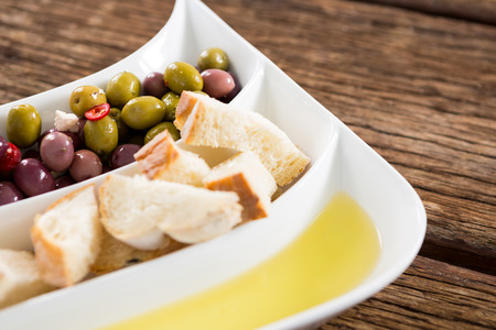 Close-up of marinated olives, bread pieces and olive oil in platterの写真素材