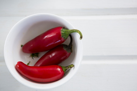 Pickled chili pepper in bowl on wooden tableの写真素材