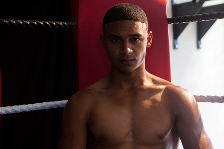 Portrait of confident man sitting in boxing ring at fitness studio