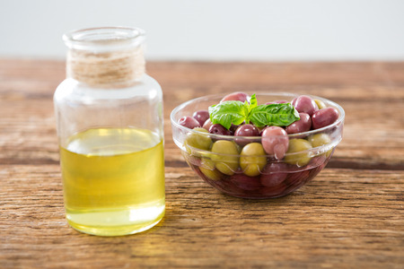 Marinated olives and olive oil on wooden tableの写真素材