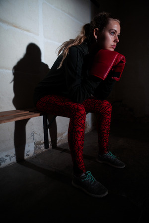 Thoughtful woman relaxing on bench in fitness studioの写真素材