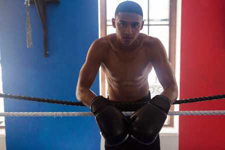 Portrait of confident man leaning on rope in fitness studioの写真素材