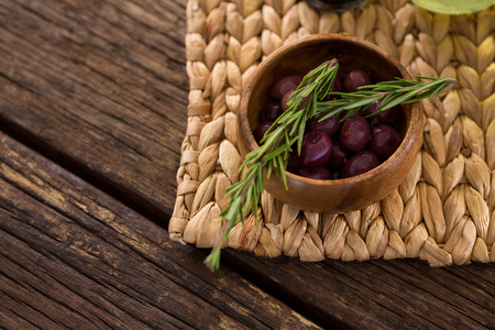 Close-up of marinated olives in bowl and rosemary herb on bamboo matの写真素材