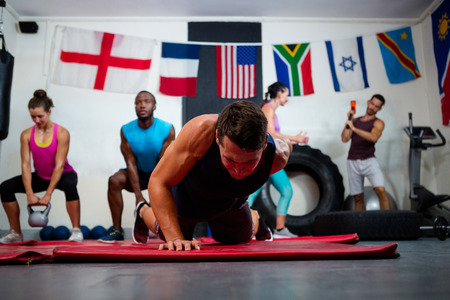 Young male athlete praticing push ups on exercise mat at fitness studioの写真素材