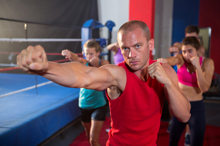 Portrait of young athlete punching by boxing ring at fitness studioの写真素材