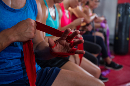 Close-up of athletes wrapping bandages at fitness studio