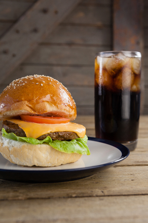 Hamburger in plate with glass of cold drink on tableの写真素材