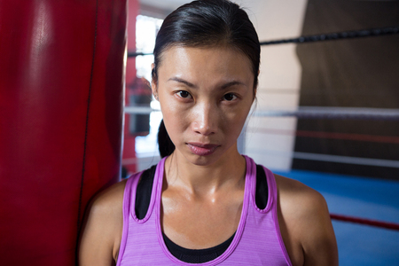 Close-up portrait of confident young female athlete against boxing ring at fitness studioの写真素材