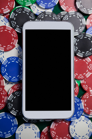 Close-up of mobile phone on multicolored casino chipsの写真素材
