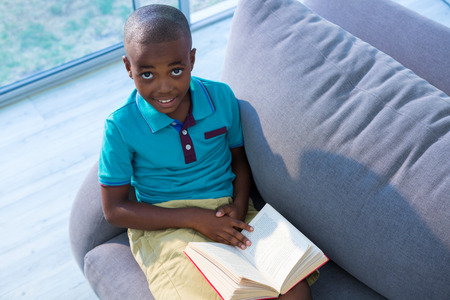 High angle portrait of boy sitting with boy on sofa in living room at homeの写真素材