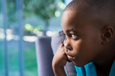 Close-up of thoughtful boy against window at homeの写真素材