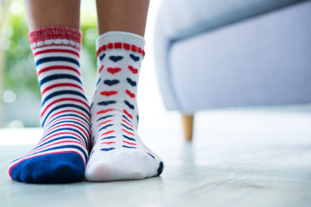Low section of girl wearing patterned socks while standing at homeの写真素材