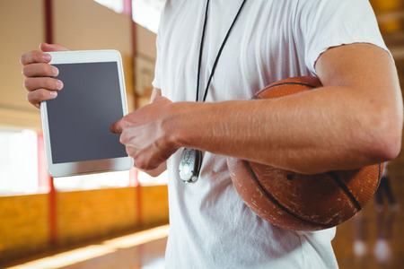 Midsection of coach showing tablet computer while standing in courtの写真素材