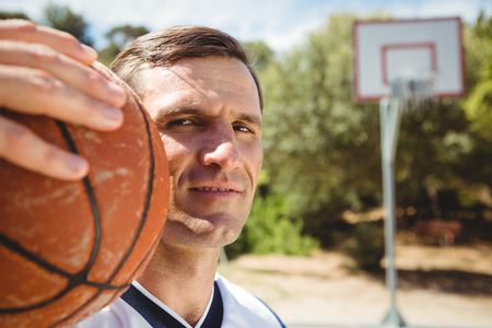 Close up portrait of confident basketball player with ball standing in courtの写真素材