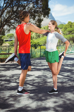 Full length of man and woman stretching on roadの写真素材