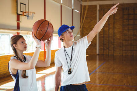 Male coach advising female basketball player while practicing in courtの写真素材
