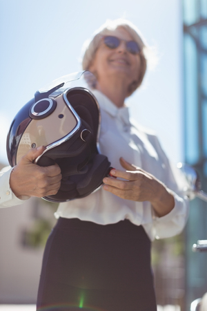 Businesswoman looking away while holding helmet on sunny dayの写真素材