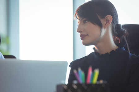 Young thoughtful woman looking away at officeの写真素材