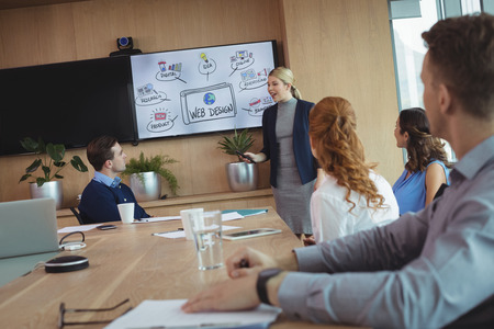 Young businesswoman interacting with colleagues during meeting in board room
