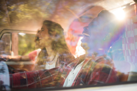 Cheerful friends in camper van seen through glass