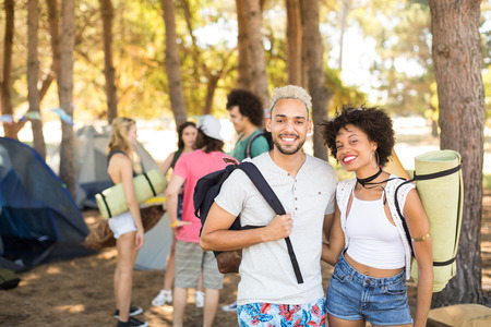 Portrait of smiling couple with friends in background at campsiteの写真素材