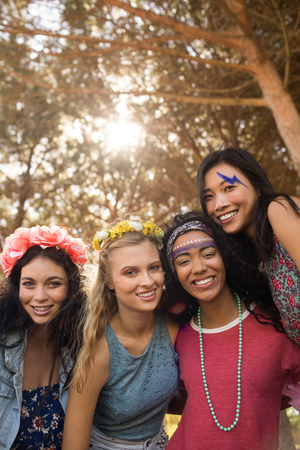 Portrait of smiling young female friends against trees at campsiteの写真素材