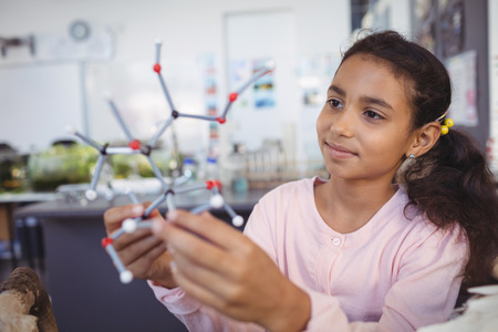 Elementary student examining molecule model at science laboratoryの写真素材