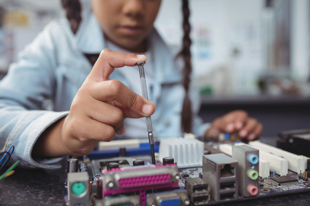 Mid section of elementary girl assembling circuit board on desk at electronics labの写真素材