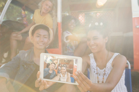 Smiling woman with friends taking selfie through digital tablet at campsiteの写真素材