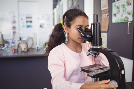 Elementary schoolgirl using microscope at science laboratoryの写真素材