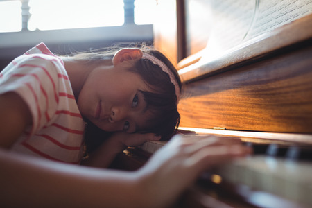 Portrait of girl leaning on piano in classroom at music schoolの写真素材