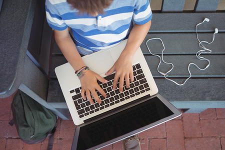 Overhead view of boy using laptop while sitting on benchの写真素材