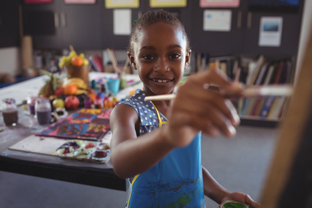 Portrait of happy girl painting on canvas in classroomの写真素材