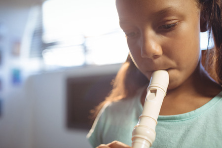 Thoughtful girl playing flute in classroom at music schoolの写真素材