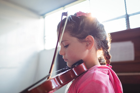 Side view of girl student rehearsing violin in music classの写真素材
