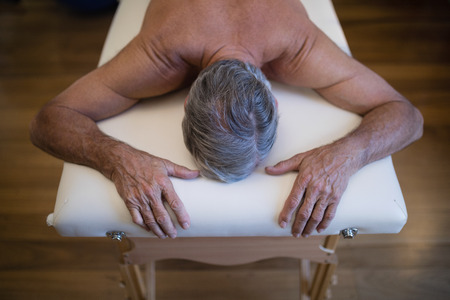 High angle view of shirtless senior male patient lying on bed at hospital wardの写真素材
