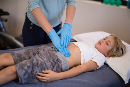 High angle view of female therapist examining stomach at hospital wardの写真素材