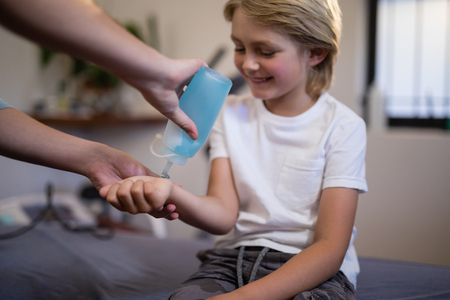 Cropped hands of female therapist pouring scanning gel on wrist at hospital wardの写真素材