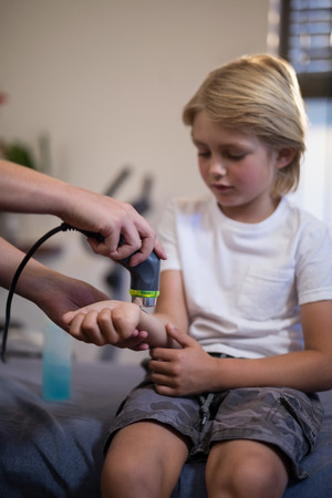 Cropped hands of female therapist pouring scanning wrist at hospital wardの写真素材