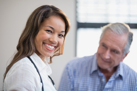 Portrait of smiling female therapist with senior male patient in background at hospital wardの写真素材
