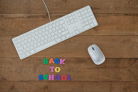 Keyboard, mouse and block letter with back to work text on wooden background