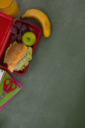 Overhead view of school supplies and lunch box arranged on chalkboardの写真素材