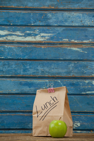 Apple and lunch bag against blue wooden backgroundの写真素材