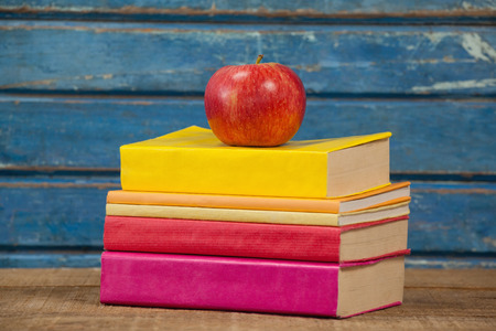 Stack of books and apple against blue wooden backgroundの写真素材