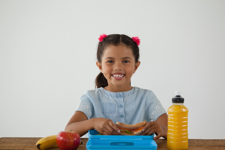 Portrait of schoolgirl having breakfast against white backgroundの写真素材