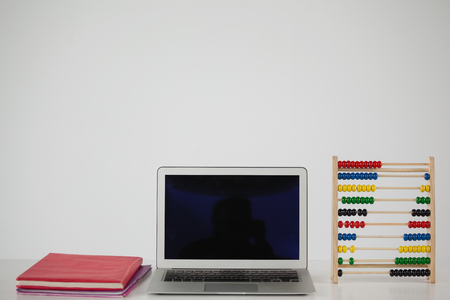 Books, laptop and abbacus against white backgroundの写真素材