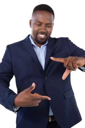 Smiling businessman forming a finger frame against white backgroundの写真素材