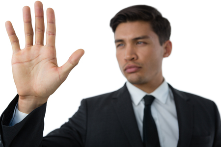 Close up of young businessman touching invisible interface against white backgroundの写真素材